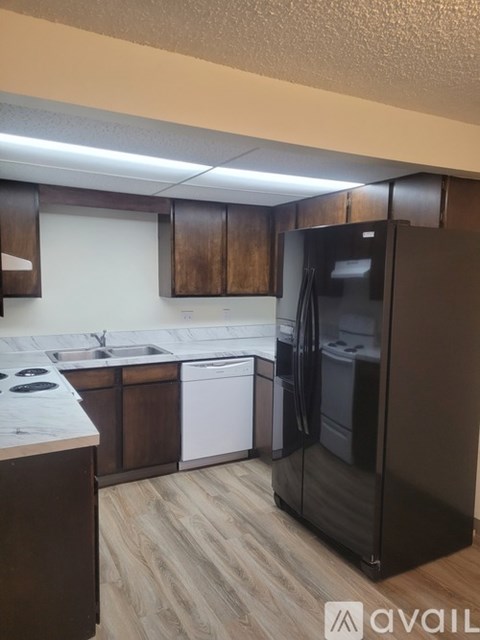 A kitchen with a black refrigerator and wooden cabinets.
