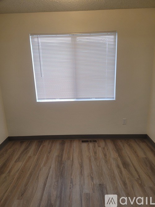 A room with wooden flooring and a window with blinds.