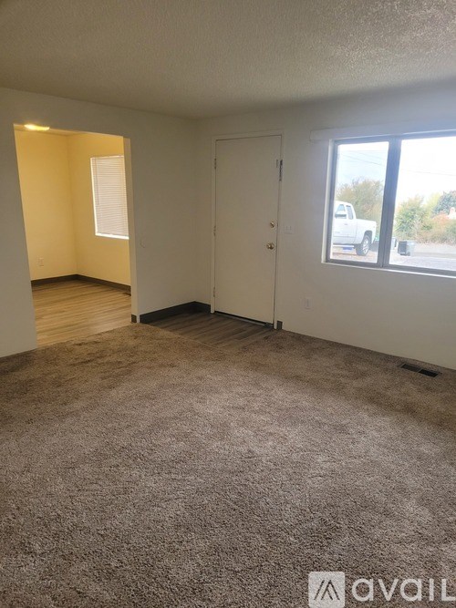 A room with a carpeted floor, a window, and a door.
