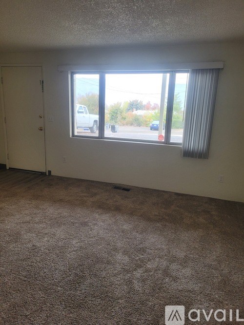 A room with a carpeted floor and a window with blinds.