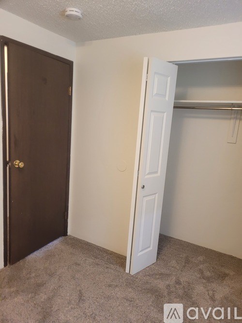 A room with a brown door and a white door with a shelf above it.