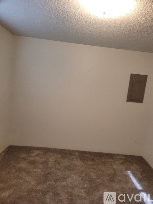 A room with a brown carpet and a white wall with a small brown square on it.