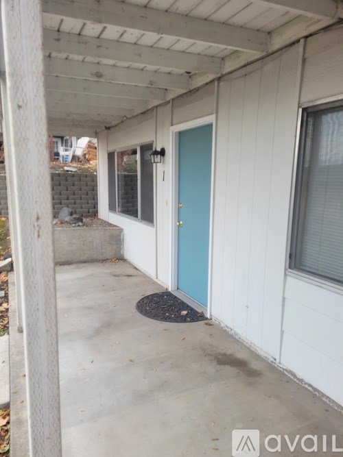 A blue door is on the right side of a white building.