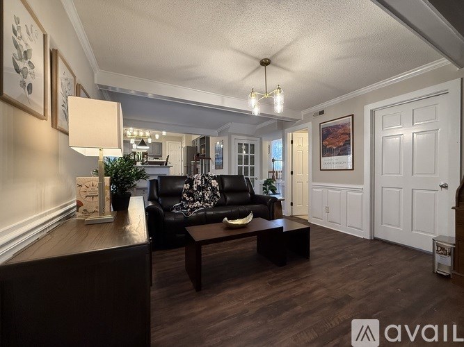A living room with a black couch and wooden floors.