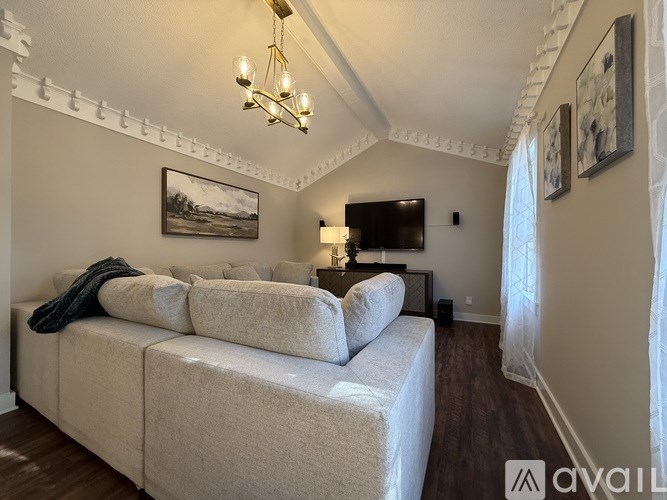 A living room with a large couch and a chandelier.