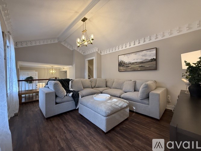 A living room with a grey couch and a chandelier.