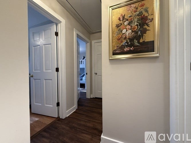 A hallway with a painting on the wall and a door on the left.