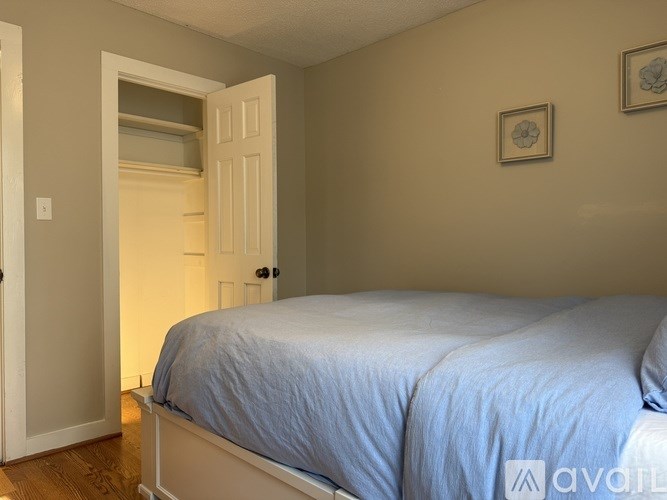 A bedroom with a bed, two pictures on the wall, and a door leading to another room.