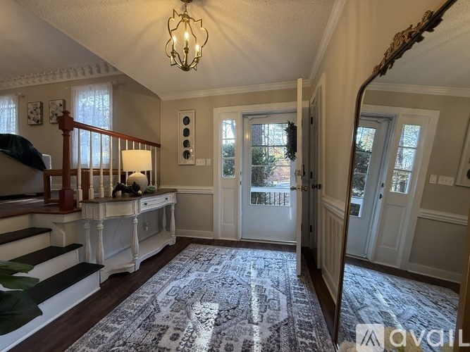 A well-lit foyer with a staircase and a rug.