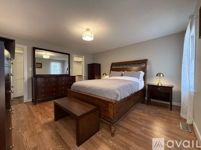 A bedroom with a large bed and a wooden floor.