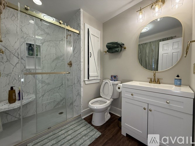 A bathroom with a marble shower and a white toilet.