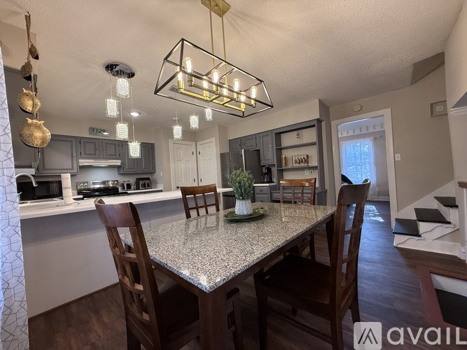A kitchen with a table and chairs in the foreground and a staircase in the background.