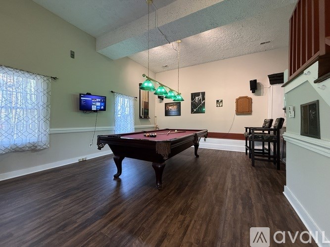 A room with a pool table and a television mounted on the wall.