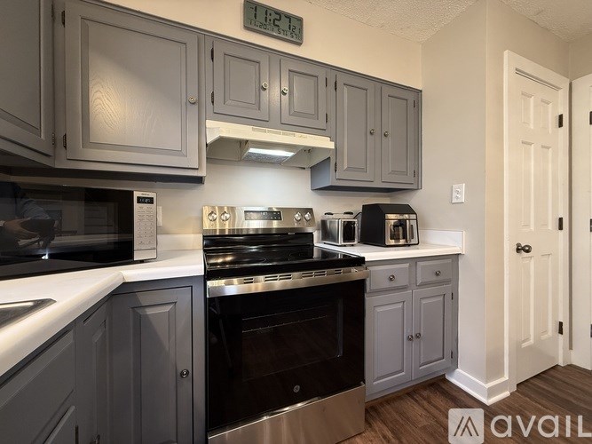 A kitchen with a black stove top oven and grey cabinets.