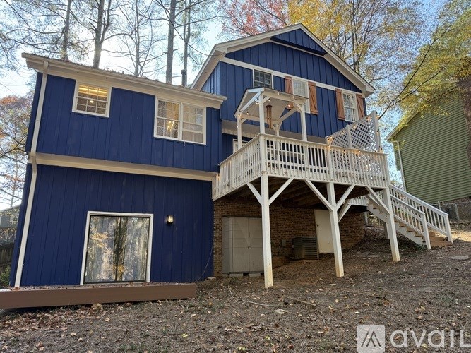 A blue house with a white porch and a brown door.
