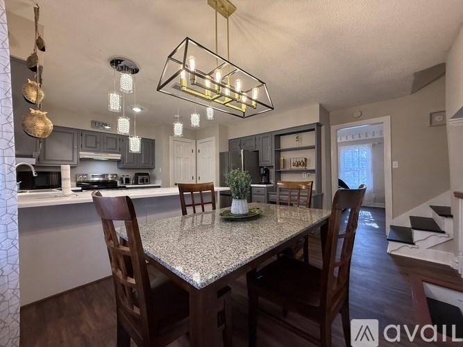 A kitchen with a table and chairs in the foreground and a staircase in the background.