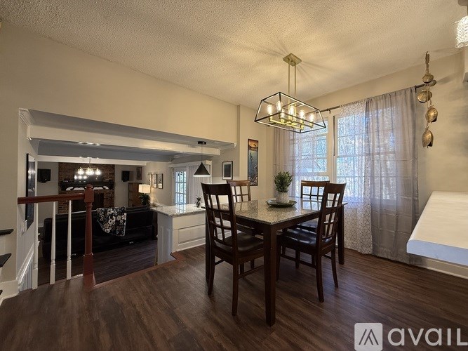 A dining room with a table set for two and a couch in the background.