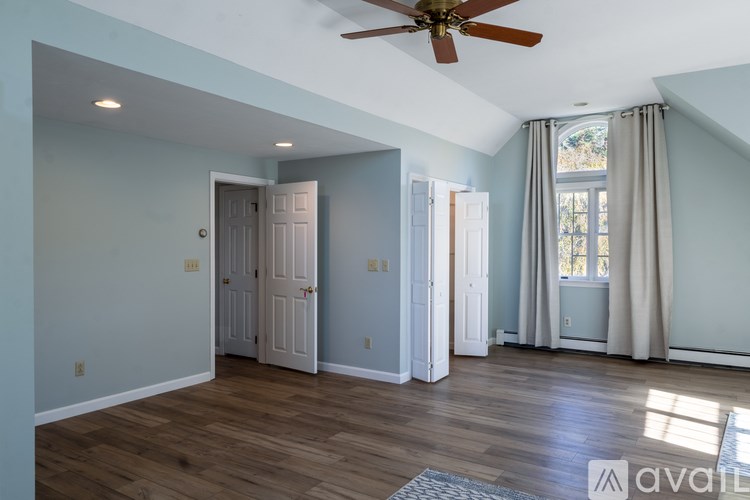 A room with a ceiling fan and a window with curtains.