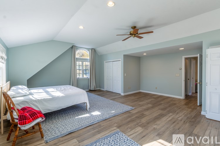 A bedroom with a bed, chair, and window.