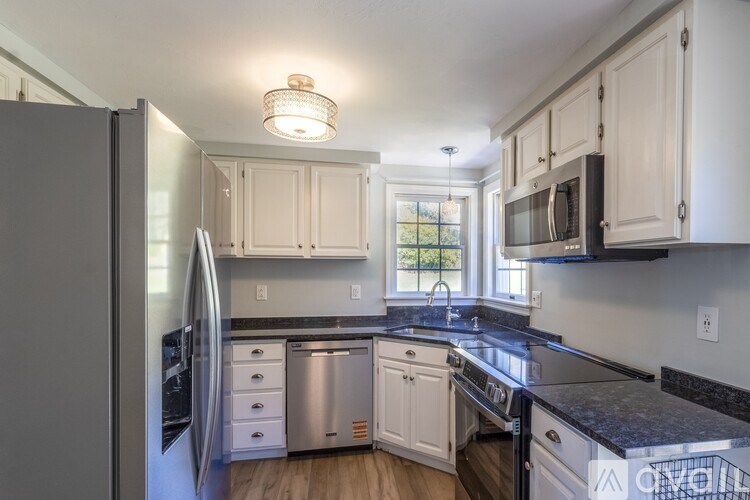 A kitchen with white cabinets and a black countertop.