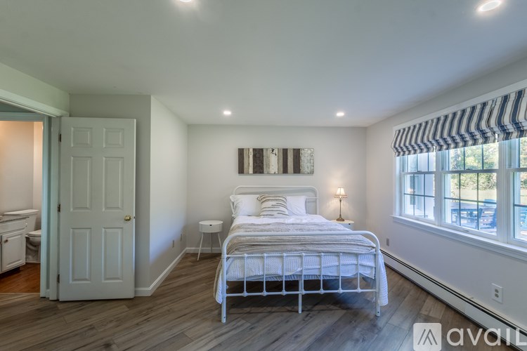 A bedroom with a bed, nightstand, and window.