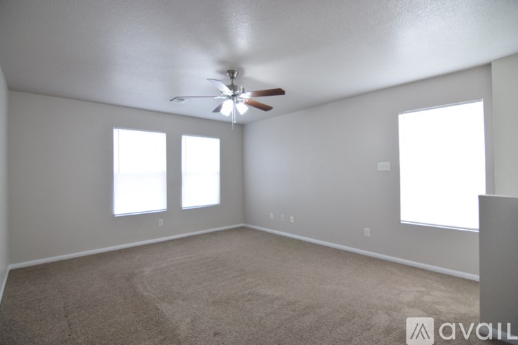 A room with a ceiling fan and carpeted floor.