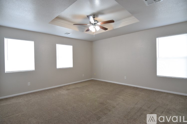 A room with a ceiling fan and three windows.