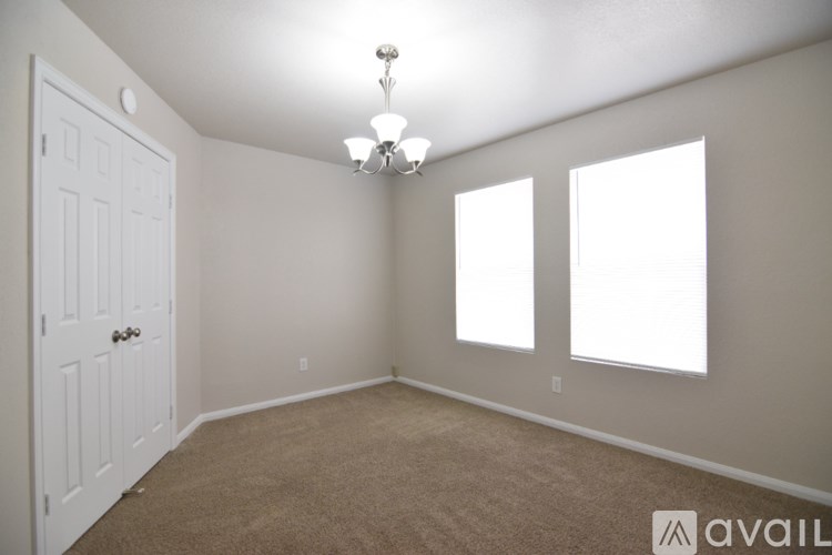 A room with a carpeted floor, a door, and two windows.