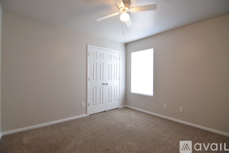 A room with a white door and a ceiling fan.