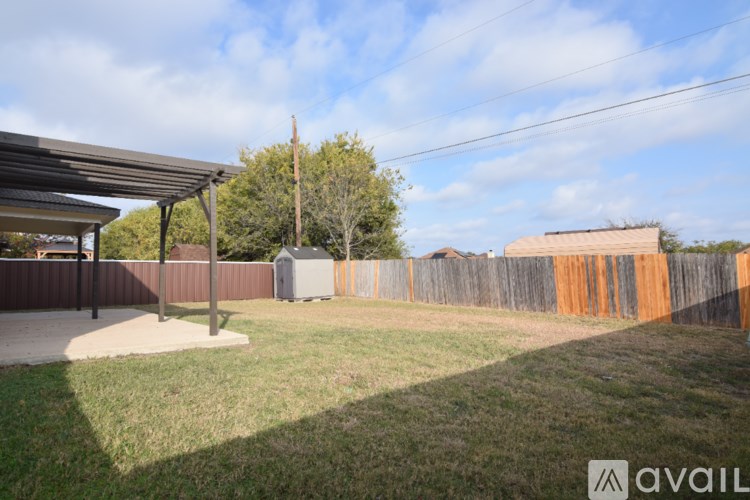 A backyard with a fence and a covered patio area.