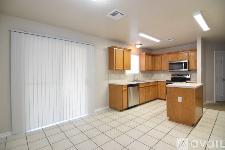 A kitchen with wooden cabinets and white tiled flooring.