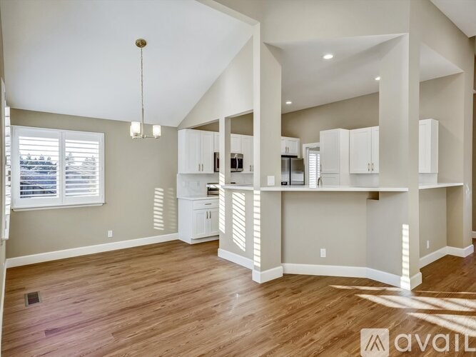 A spacious kitchen with white cabinets and a wooden floor.