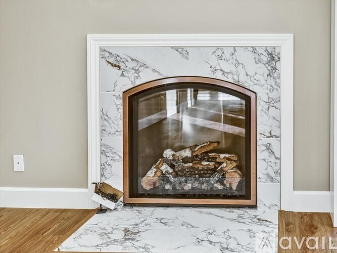 A fireplace with a white marble mantle and a wood burning fire.