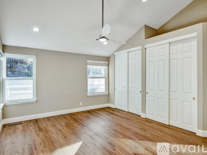 A room with wooden floors and white doors is available for rent.