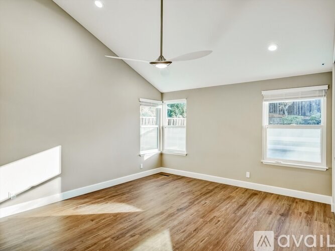 A room with a ceiling fan and a window with a view of a fence.