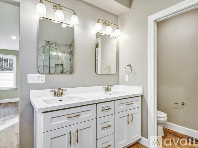 A bathroom with a vanity, two mirrors, and a toilet.