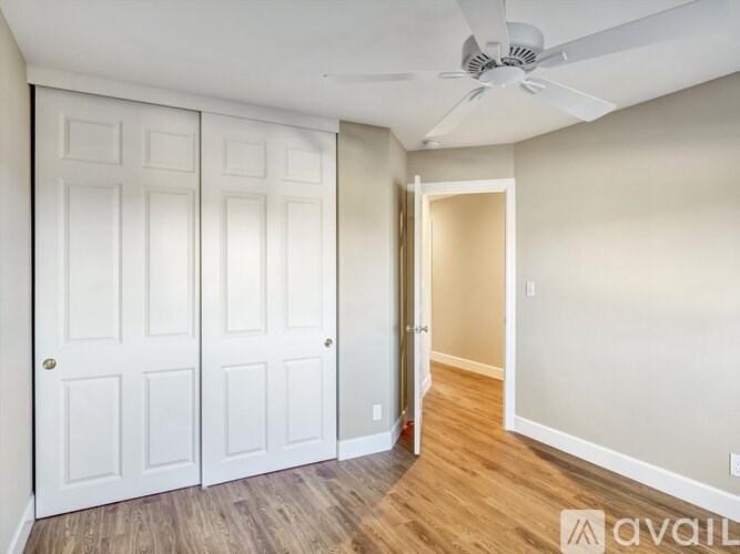 A room with a ceiling fan and a door on the left.