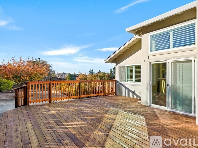 A wooden deck with a railing and a house in the background.