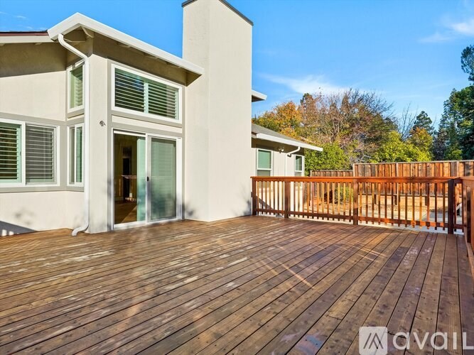 A wooden deck leads to a modern house with a glass door.