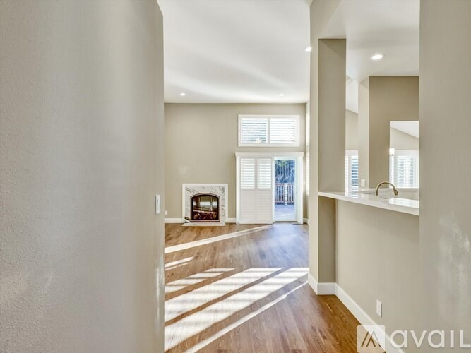 A spacious room with a fireplace and a view of the backyard through the window.