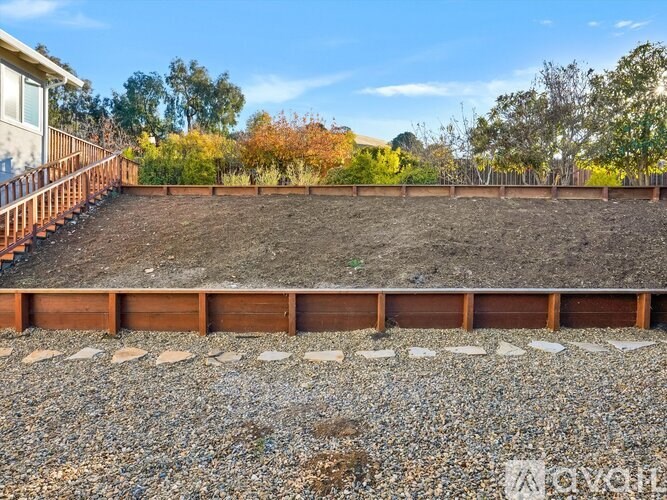 A backyard with a gravel area and a wooden fence.
