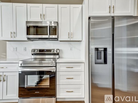 A modern kitchen with white cabinets and stainless steel appliances.