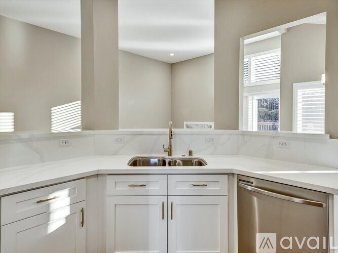 A modern kitchen with white cabinets and a stainless steel refrigerator.