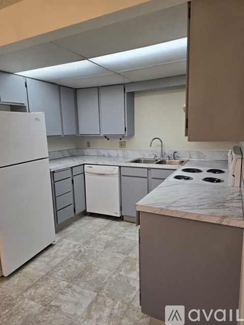 A kitchen with a white refrigerator, a white dishwasher, and a marble countertop.
