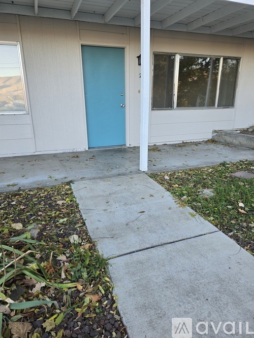 A blue door is on the left side of a white building.