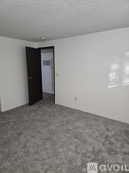 A room with a carpeted floor and a door leading to another room.