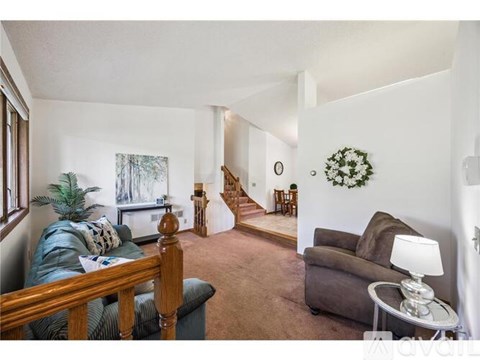 A living room with a couch, a chair, and a table with a lamp on it.