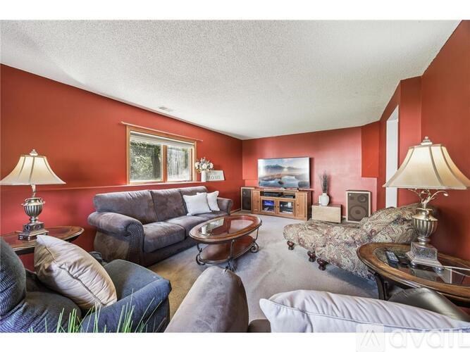 A living room with a grey couch and a red wall.