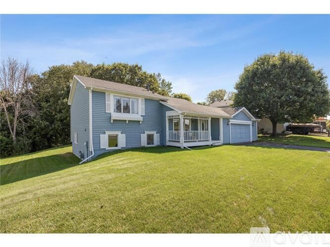 A blue house with a white porch and a green lawn.