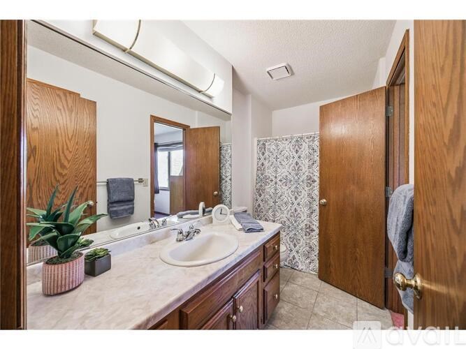 A bathroom with a sink, mirror, and wooden cabinets.
